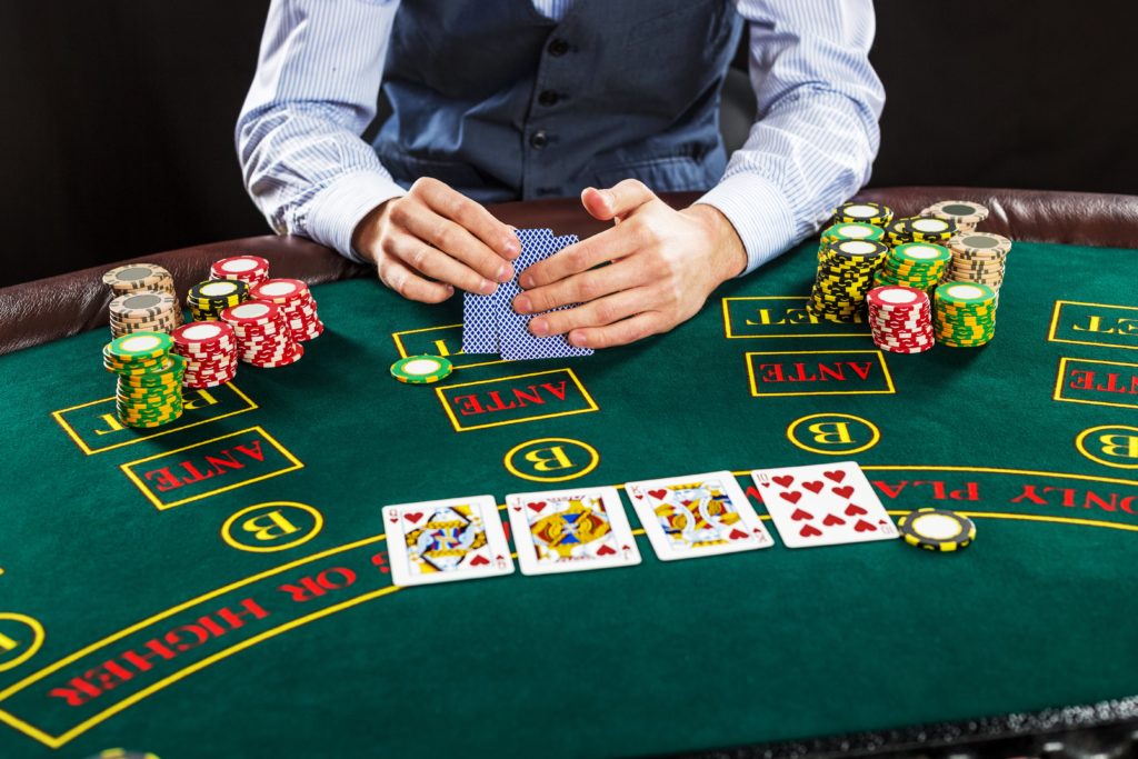 close-up-poker-player-with-playing-cards-chips-green-casino-table
