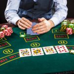 close-up-poker-player-with-playing-cards-chips-green-casino-table